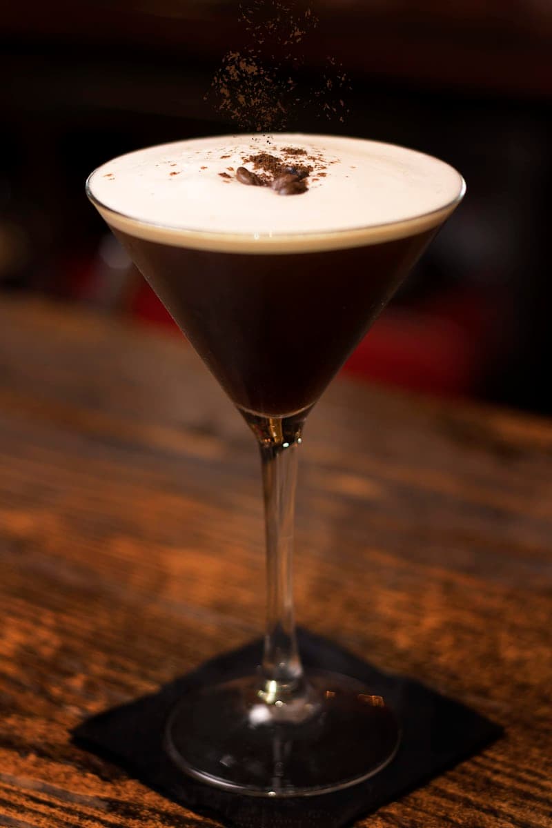 Espresso Martini in a coupe with a pale foam cap and coffee dust over a warm bar