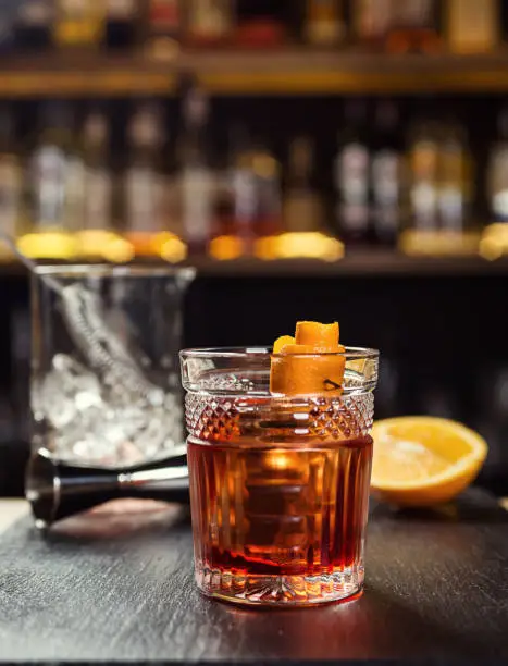 Amber Old Fashioned in a rocks glass with an orange peel and blurred backbar